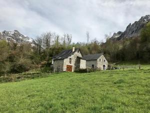 una casa vieja en un campo con montañas en el fondo en Petit aoulet, en Accous