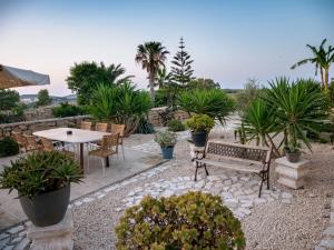 a patio with a table and chairs and plants at VinDor Villa in Sannat