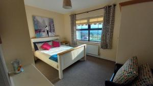 a bedroom with a bed with red pillows and a window at Cuckoo Tree House Glengarriff Beara Peninsula in Glengarriff