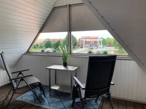 eine Veranda mit 2 Stühlen, einem Tisch und einem Fenster in der Unterkunft HAusZeit Kapitänshaus Friedrichsschleuse in Carolinensiel