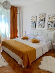 1 dormitorio con 1 cama blanca grande con sábanas de color naranja en Roman Forum Apartments, en Zadar