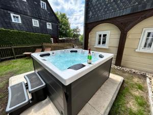 a hot tub in a yard with a bottle of champagne at Ferienhaus Hexe mit Whirlpool, Sauna, Garten in Großschönau