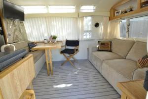 sala de estar con sofá y mesa en Airstream Retro USA caravan, en Earnewâld