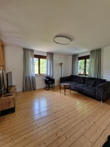 a living room with a black couch and a wooden floor at Lindenwohnung an historischer Mühle in Holzhausen