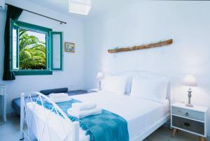 Un dormitorio blanco con una cama blanca y una ventana en ANCIENT MEROPIA - Les jardins des muses, en Apollonia