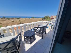 balkon z 2 krzesłami i stołem oraz widokiem na ocean w obiekcie Villa Amavi Peyia w Pafos