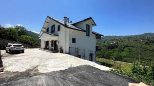 una casa blanca con un coche aparcado en una entrada en Greenplain Smurf, en Trabzon