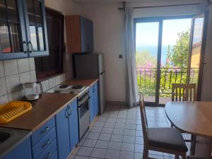 a kitchen with blue cabinets and a table and a window at Apartment Camelia in Opatija