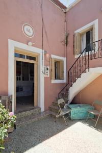 a pink house with two chairs and a staircase at Traditional Karpathian house in Karpathos Town