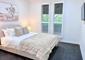 a white bedroom with a bed and two windows at Executive living in City fringe location in Glenunga