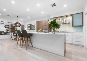 una cocina con armarios blancos y una barra con sillas en Executive living in City fringe location en Glenunga
