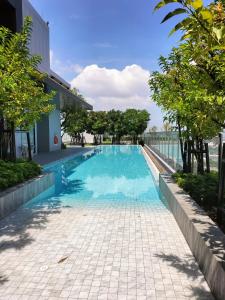 a swimming pool next to a building with trees at Two bedroom condo with rooftop pool in Ban Talat Rangsit