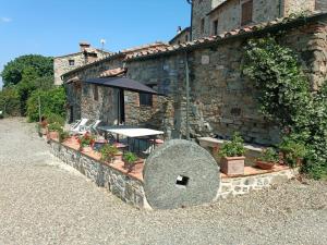 un edificio in pietra con tavolo e ombrellone di Borgo Cerbaiola a Montecastelli