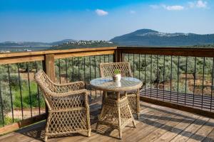 una mesa y 2 sillas en una terraza de madera en צימר בכפר - סוויטות ובקתות מקסימות עם בריכה במתחם ונוף מהמם, en Rama