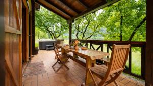 eine Veranda mit einem Holztisch und Stühlen darauf in der Unterkunft Holiday House Sofia in Delnice