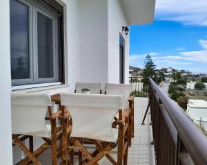 a balcony with white chairs and a table and a window at Preet House in Víssa