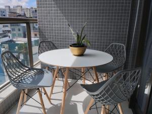 uma mesa branca com cadeiras e um vaso de plantas numa varanda em Barra Pinauna Studio em Salvador