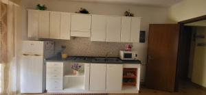 una piccola cucina con armadietti bianchi e forno a microonde di Sperry's house Porto Torres a Porto Torres