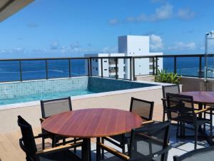 a balcony with a table and chairs and a swimming pool at Barra Pinauna Studio in Salvador