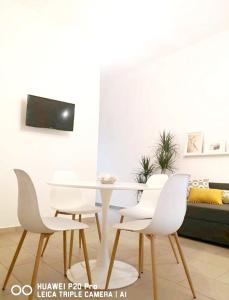 a dining room with a white table and white chairs at Mare & Vento in Torre Lapillo