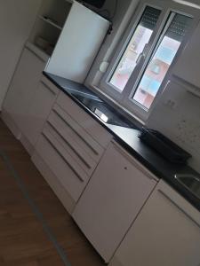 a kitchen with white cabinets and two windows at Apartments Matanovic in Rogoznica