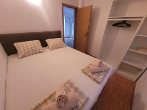 a bedroom with a large white bed with two pillows at Apartments Matanovic in Rogoznica