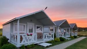 a row of cottages with a sunset in the background at BIAŁE DOMKI in Rusinowo