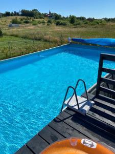 a swimming pool with a chair next to the water at BIAŁE DOMKI in Rusinowo