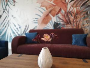 a vase with flowers on a table in front of a couch at Alison Apartments (Nr. 24) in Keszthely