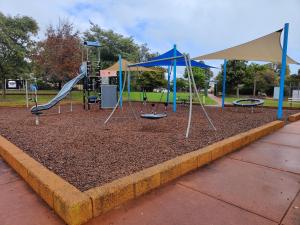 a playground with swings and slides in a park at The Cozy little House in Armadale