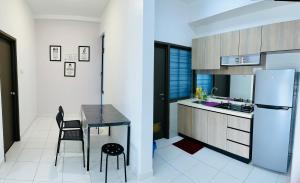 una pequeña cocina con mesa y nevera en J&R Homestay Johor Bahru near Austin Southkey CIQ Singapore, en Kangkar Teberau