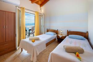 two beds in a room with a view of the ocean at Villa Avgerini Paxos in Gaios