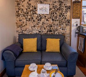 a blue couch with two yellow pillows and a table at All Seasons Cottage Breaks in Saxmundham