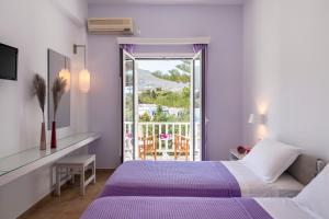 sypialnia z fioletowym łóżkiem i balkonem w obiekcie Doukissa w mieście Parikia
