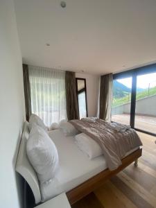 un letto bianco in una stanza con una grande finestra di Schooren des Alpes Luxury Apartments a Kappl