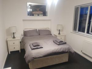 ein Schlafzimmer mit einem Bett mit zwei Nachttischen und zwei Fenstern in der Unterkunft The hawthorns large detached 3 bedroom family home in Seaham