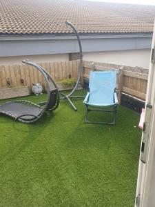 a blue chair sitting on the grass in a backyard at The hawthorns large detached 3 bedroom family home in Seaham