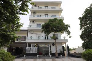 budynek z drzewem przed nim w obiekcie Opulent Inn by Lime Tree Hotels w mieście Greater Noida