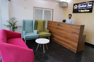 Ein Mann steht an einer Theke in einem Zimmer mit zwei Stühlen in der Unterkunft Opulent Inn by Lime Tree Hotels in Greater Noida