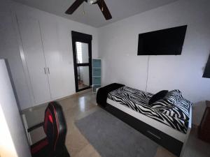 Casa con picina en Granada. في البولوتي: غرفة نوم مع سرير مطبوع حمار وحشي وتلفزيون بشاشة مسطحة