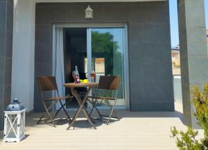einen Tisch mit 2 Stühlen und Weingläsern auf einer Terrasse in der Unterkunft Bungalow en Punta Prima 2 dormitorios y piscina in Torrevieja