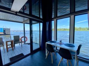 Habitación con mesa, sillas y vistas al agua. en Hausboot- Domy na wodzie - Houseboat Porta Mare, en Kamień Pomorski