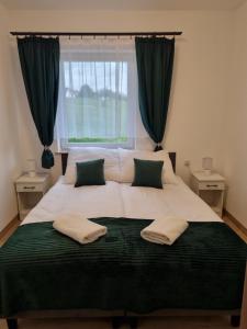 a bedroom with a large bed with green curtains at Apartamenty Jeleń Pod Grapom in Bańska Niżna