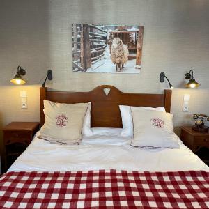 - un lit avec deux oreillers et une photo d'un mouton dans l'établissement Hôtel du Lion d'Or, à Cauterets
