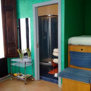ein Badezimmer mit Dusche und ein Schlafzimmer mit grünen Wänden in der Unterkunft B&B L’Angolo sulla Piazza in Mirabella Imbaccari