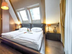 a bedroom with a bed with white sheets and two windows at VisitZakopane - Mango Apartment in Zakopane