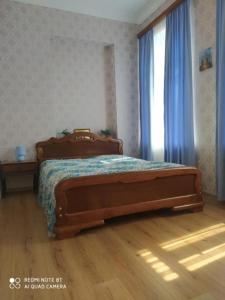 1 dormitorio con 1 cama y una ventana con cortinas azules en House at the Forest / სახლი ტყის პირას, en Gordi