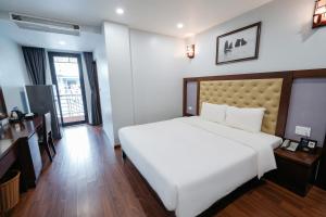 a bedroom with a large white bed and a desk at Topone Halong Hotel in Ha Long