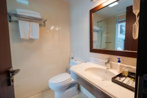 uma casa de banho com um lavatório, um WC e um espelho. em Topone Halong Hotel em Ha Long