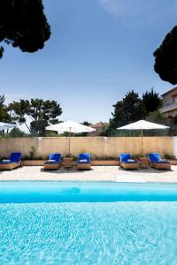 a group of lounge chairs and umbrellas next to a swimming pool at Hôtel du Parc Cavalaire sur Mer in Cavalaire-sur-Mer
